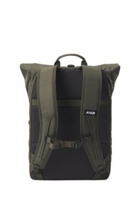 Backpack in olive green fabric with padded mesh straps, roll-top design, adjustable buckle, and logo detail on front.