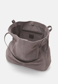 Szara zamszowa torba typu tote z przestronnym wnętrzem, wyposażona w gładką skórzaną rączkę oraz wewnętrzną kieszeń z dyskretną metką marki.