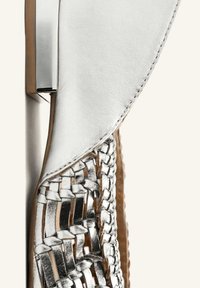 Sandalo in pelle intrecciata argento metallizzato con tomaia liscia, dettagli intrecciati intricati e un elegante accento rettangolare argentato.