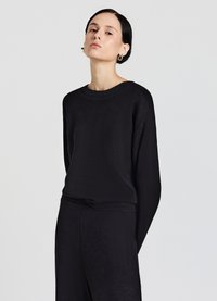 Maglione nero con scollo rotondo, vestibilità comoda e polsini a coste. Tessuto dalla consistenza morbida, abbinato a pantaloni coordinati. Design semplice.
