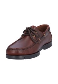 Zapato de barco de cuero marrón con puntera redonda, detalles de costura, suela de goma negra y ojales en tono dorado para los cordones.