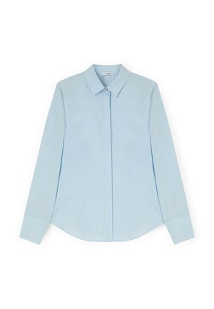 Camisa azul claro de manga larga con botones, cuello puntiagudo y botones delanteros ocultos, extendida sobre un fondo blanco.