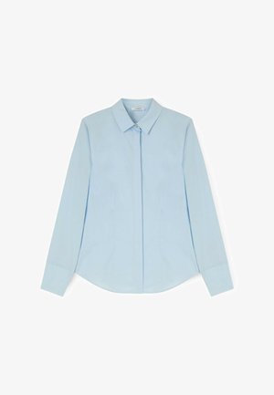 Camisa azul claro de manga larga con botones, cuello puntiagudo y botones delanteros ocultos, extendida sobre un fondo blanco.