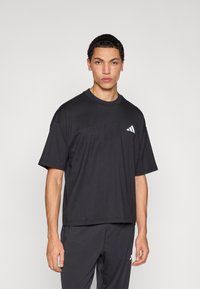 Černé tričko s krátkými rukávy a kulatým výstřihem, s nenápadným logem na hrudi. Vyrobené z měkké bavlny, pohodlný střih, minimalistický design.