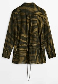 Chemise à manches longues sans col en tissu transparent avec un imprimé animalier vert foncé et or. Dotée d'une taille cintrée et de poignets boutonnés.