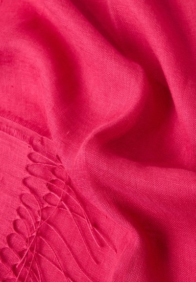 Φωτεινό ροζ ύφασμα με απαλά πτυχώσεις και φούντες σε μία από τις άκρες.