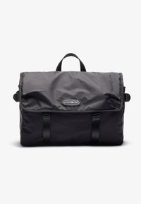 Black nylon messenger bag with a flap closure, top handle, and adjustable straps; features logo and contrasting trim.