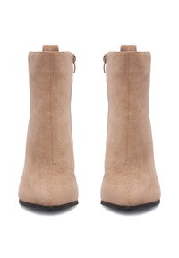 Béžové semišové členkové čižmy s elegantným siluetou, uzavretou špičkou a zipsom na zadnej strane. Čierna podrážka dokončuje dizajn.