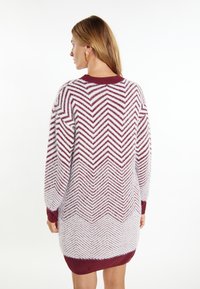 Rochie tricotată cu un model în dâmburi în alb și burgund, cu un guler rotund cu perlă și mâneci lungi. Textură netedă.