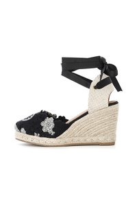Wedge in espadrille nera con ricami floreali, suola in juta, tomaia in tessuto stampato e lacci neri alla caviglia che fissano un pannello posteriore intrecciato.