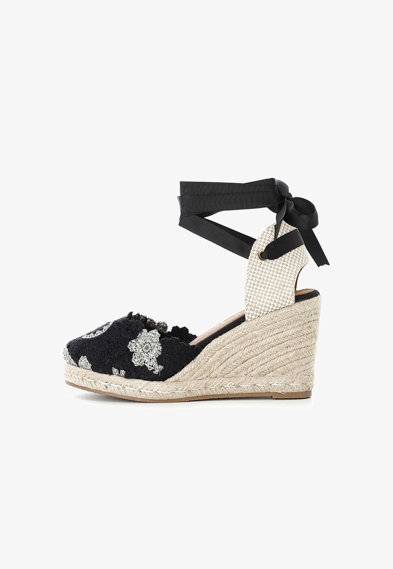 Wedge in espadrille nera con ricami floreali, suola in juta, tomaia in tessuto stampato e lacci neri alla caviglia che fissano un pannello posteriore intrecciato.