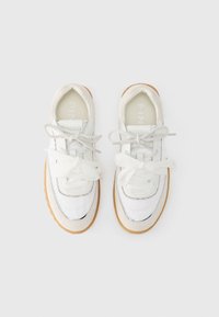 Λευκά αθλητικά παπούτσια με συνδυασμό λείων και υφασματικών υλικών, στρογγυλεμένη μύτη, εμφανή στοιχεία από δίχτυ και αντανακλαστικές ασημί λεπτομέρειες στα πλάγια.