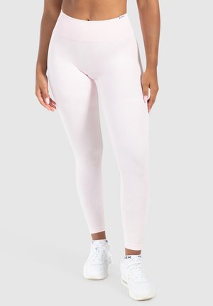 Leggings a vita alta di colore rosa chiaro realizzati in tessuto elastico, con una texture liscia e un design senza cuciture, abbinati a sneakers bianche.