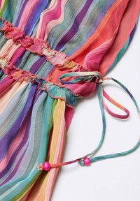 Mehrfarbiges Kleid mit vertikalen Streifen in den Farben Pink, Lila, Türkis und Gelb. Verfügt über Volants und pinkfarbene Perlenakzente an den Bindebändern.
