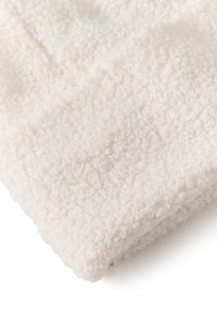 Biely textúrovaný materiál, ktorý má mäkký, chlpatý povrch s malými slučkami. Tento materiál vyzerá nadýchane a vykazuje rovnomernú farbu a hrúbku.