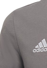 Grijze sweatshirt met een textuurstof, voorzien van een witte geborduurde drie-strepenlogo op de linkerborst en een ronde hals.