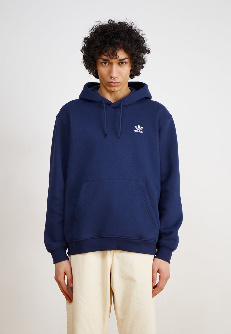 Navyblauwe hoodie van zacht materiaal, met een kangoeroezak, wit Adidas-logo op de borst en een capuchon met trekkoord.