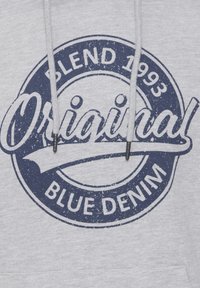 Šedá mikina s velkým námořnickým modrým kruhovým logem. Text zní "Original Blend 1993 Blue Denim" a má strukturovaný, opotřebovaný vzhled.