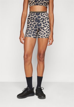 Fitness shorts med leopardmønster og høj talje, lavet af strækbart materiale. Sammen med sorte træningssko og sokker.