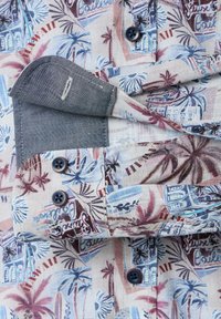 Kurzarmshirt mit einem bunten tropischen Druck, der Palmen und Gebäude zeigt. Hergestellt aus Stoff mit strukturiertem Finish; sichtbare blaue Knöpfe.