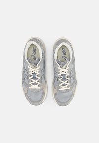 Šedé sportovní boty s vrchním materiálem z síťoviny a semiše, s polstrovaným límcem, kontrastními bílými tkaničkami a zesílenou špičkou.