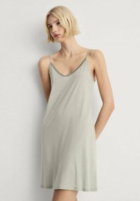 Ljusgrön ärmlös klänning med v-ringning och delikat spetskant vid halslinningen. Mjuk tyg, avslappnad siluett, knälång design.
