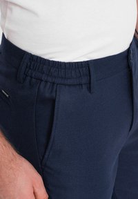 Pantalons bleu marine en tissu texturé, avec une taille élastique et des poches latérales. Conçus pour le confort avec une coupe ajustée.