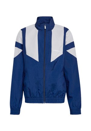 Adidas vindjakke i marineblåt og lysegråt med fuld lynlås foran, høj krave, elastiske ærmegab og talje samt logo på brystet.