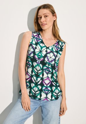 Top senza maniche con scollo a V, caratterizzato da un motivo geometrico in teal, bianco e viola su un tessuto leggero. Abbinato a jeans azzurri.