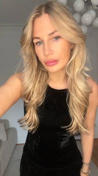 Schwarzes ärmelloses Samtkleid mit figurbetonter Silhouette, langem welligem blondem Haar und einem einfachen silbernen Armband am Handgelenk.