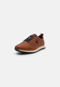 Bottines en cuir perforé marron avec des lacets bleu marine, une semelle intermédiaire blanche et une semelle extérieure en caoutchouc noir. Présente un accent de logo sur le côté.