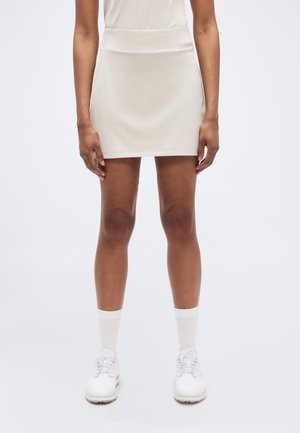 Λευκή φούστα από πολυεστέρα με απλό σχέδιο, μήκος μέχρι το μέσο του μηρού, με φαρδιά μέση και λεία υφή. Φοριέται με λευκά παπούτσια και κάλτσες.