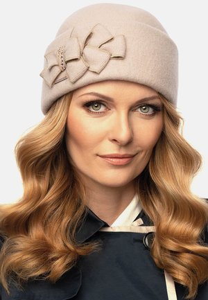 Beige vlněný klobouk cloche s velkou látkovou mašlí s akcenty z rhinestone. Hladký povrch a zaoblený tvar s pevnou sedící.