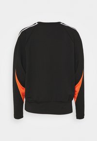 Sweat-shirt noir à manches longues, avec des accents en maille orange sur les côtés et des rayures blanches le long des épaules. Texture lisse.