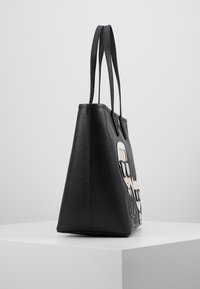 Zwarte tas met een gestructureerd oppervlak, voorzien van grafische illustraties aan één kant, dubbele platte handgrepen en een gestructureerde driehoekige vorm.