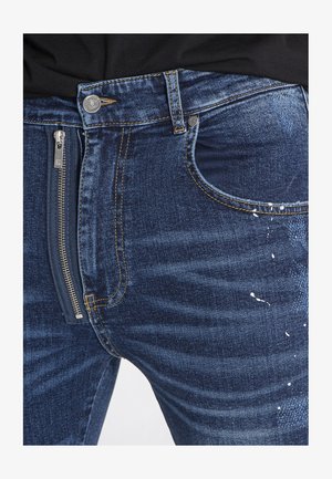 Dunkelblaue Denim-Jeans mit einer Reißverschlusstasche vorne. Mit leichter Abnutzung und kontrastierendem Nähdetail.