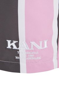 Šortky vyrobené z mäkkej textílie s vertikálnymi pruhmi v čiernej, bielej a ružovej farbe. Vyšívané logo znie "KANI" s nápisom "THE ORIGINAL EST. 1989."