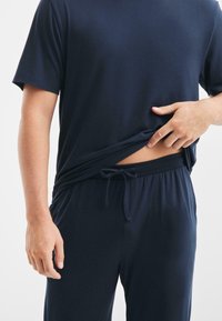 Set di abbigliamento loungewear in misto cotone di colore blu navy, composto da una maglietta a maniche corte e pantaloni con cordoncino, che offrono una trama morbida e una vestibilità comoda.