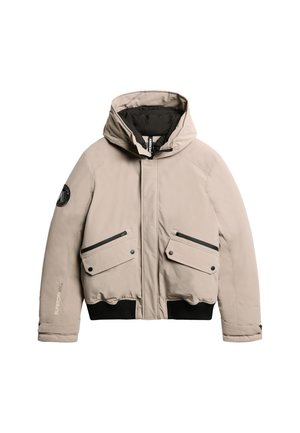 Beige donsjack met een capuchon, zwarte voering, twee voorzakken met klep en ribgebreid zoom. Beschikt over een logopatch en ritszakken.