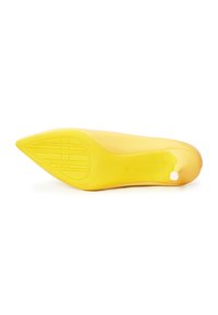 Zapato de tacón alto amarillo con punta afilada, superficie lisa y suela de goma texturizada que presenta patrones de banda de rodadura lineales y un pequeño acento en el tacón.