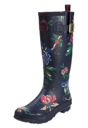 Botte de pluie haute bleu marine avec des motifs floraux en rouge, bleu, vert et beige, dotée d'une boucle latérale et d'un patch de marque près du haut.