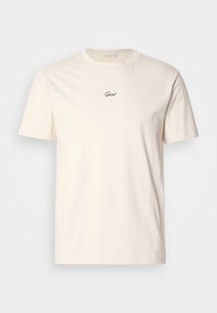 Kremfarget bomulls T-skjorte med korte ermer og rund hals. Har en liten svart brodert logo på brystet. Myk tekstur.