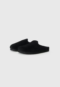 Black suede slip-on clogs with a soft upper, rounded toe, and textured rubber sole for grip. No visible closures or embellishments.