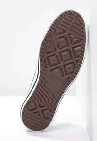 Semelle en caoutchouc marron pour baskets avec un motif de sculpture géométrique, bord blanc, et logo "Converse All Star" près du talon.