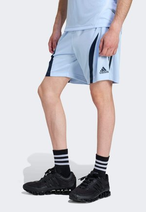 Hellblaue Sportshorts mit marineblauen Seitenpanelen, kombiniert mit schwarzen Sportschuhen und schwarzen Socken mit weißen Streifen.