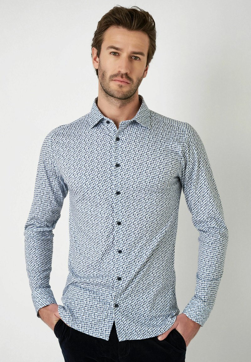 Lichtblauw button-up shirt met een geometrisch marineblauw patroon. Lange mouwen, kraag en zwarte knopen. Gemaakt van een gladde stof.