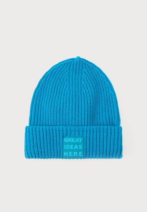 Blå strikket lue med ribbestruktur og brettet mansjett. Har en rektangulær lapp med "GREAT IDEAS HERE" i fet skrift.