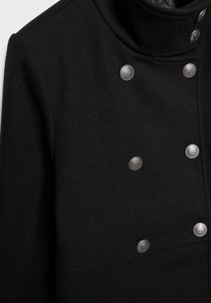 Crni kaput od vune s visokim ovratnikom, sadrži šest metalnih dugmadi sprijeda i teksturiranu tkaninu na površini.