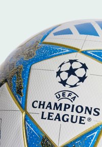 Vit fotboll med blå och guld detaljer. Har UEFA Champions League-logotypen och dekorativa mönster på en texturerad yta.