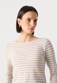 Stripet langermet skjorte i myk beige og kremfarge. Lett materiale med en svak glans, med en vid hals og tettsittende ermer.